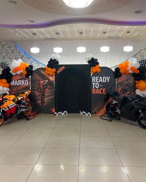 Moto tema za 18. rođendan sa dva motocikla, narandžastim i crnim balonima i trkačkim panoima