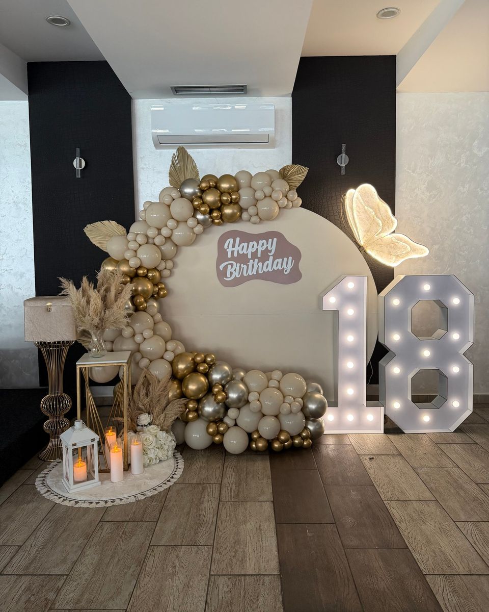 Okrugli panel sa natpisom Happy Birthday, bež i zlatni baloni, pampas i broj 18 sa sijalicama