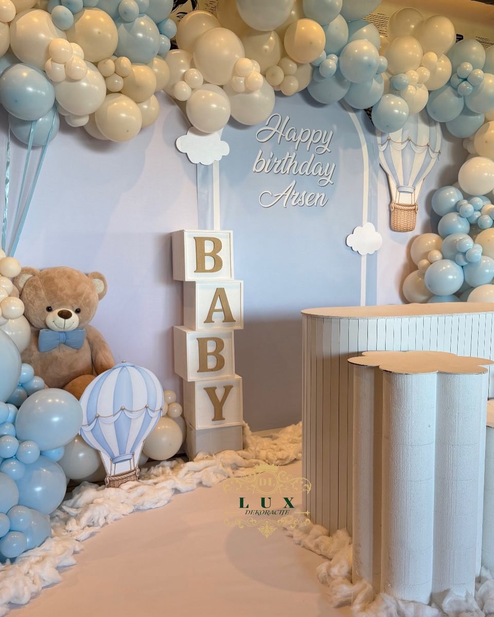 Dekoracija za prvi rođendan sa plavim i belim balonima, kockama BABY, medom i belim postoljima