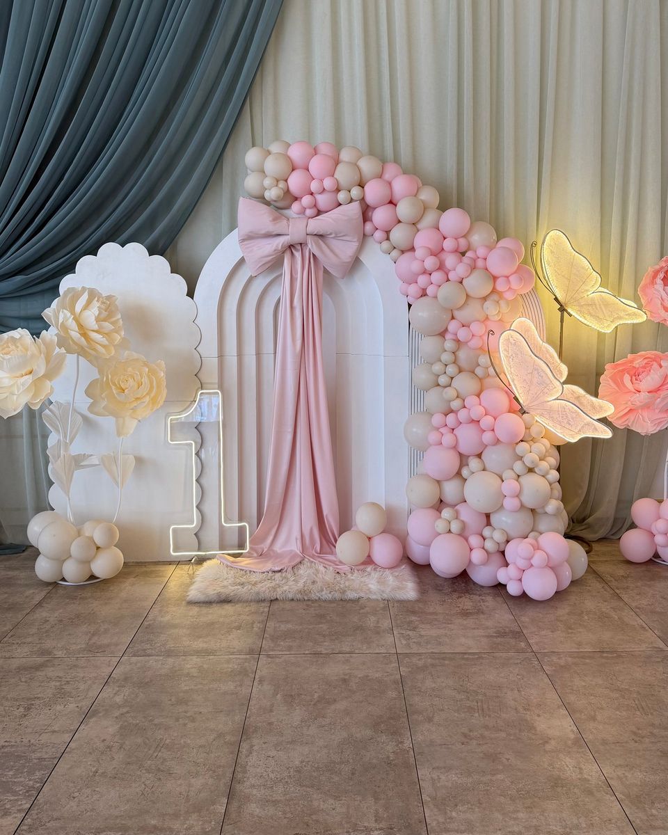 Beli lukovi sa roze mašnom, roze balonima, belim cvećem, velikim roze cvetom i brojem 1