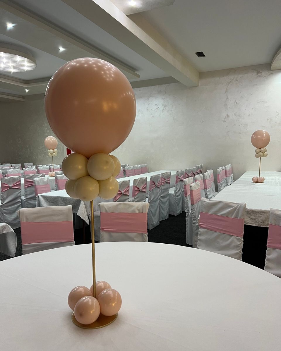 Balon boje breskve na zlatnom štapu sa bazom od balona na belom stolu