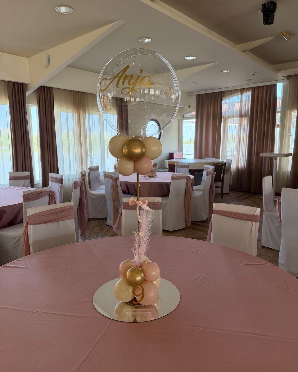 Providni balon sa zlatnim imenom slavljenice i zlatni i krem baloni na roze stolnjaku