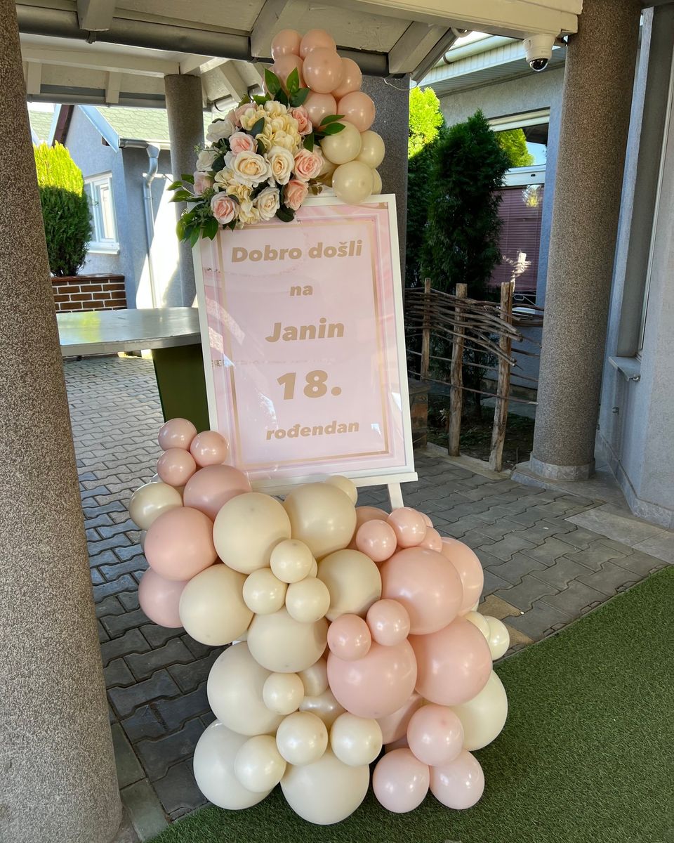Roze tabla za 18. rođendan sa ružama i breskva i krem balonima ispred ulaza