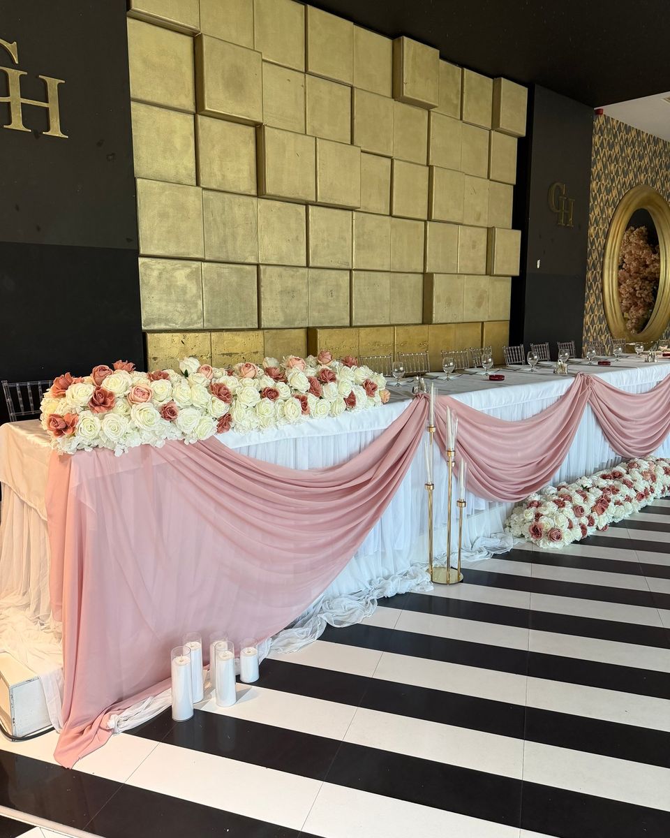 Dug glavni sto sa roze draperijom, belim i bordo ružama i zlatnim svećnjacima