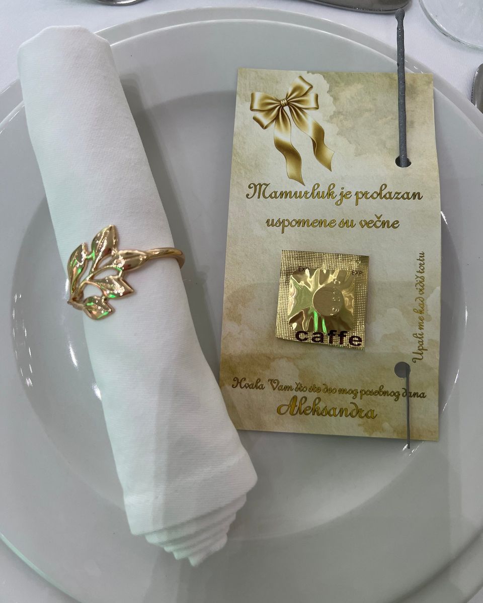 Zahvalnica sa kesicom kafe pored bele salvete sa zlatnim prstenom za salvetu